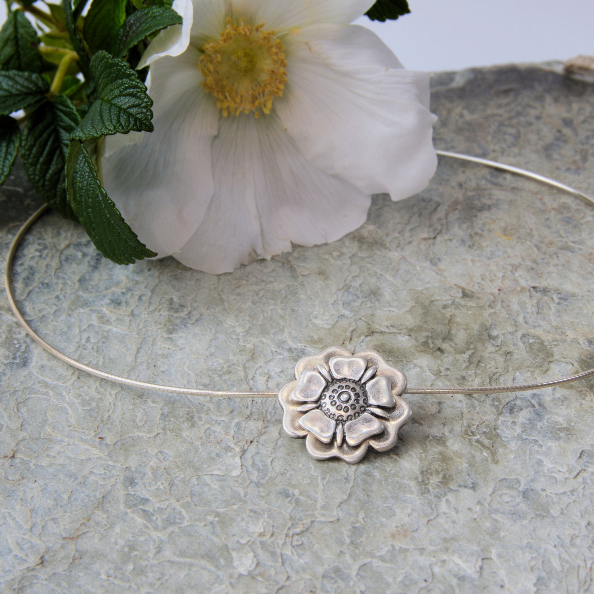 Outlander Jacobite Rose Coin Collection necklace with rose charm on a slate background with rose by Aurora Jewellery, Orkney, Scotland