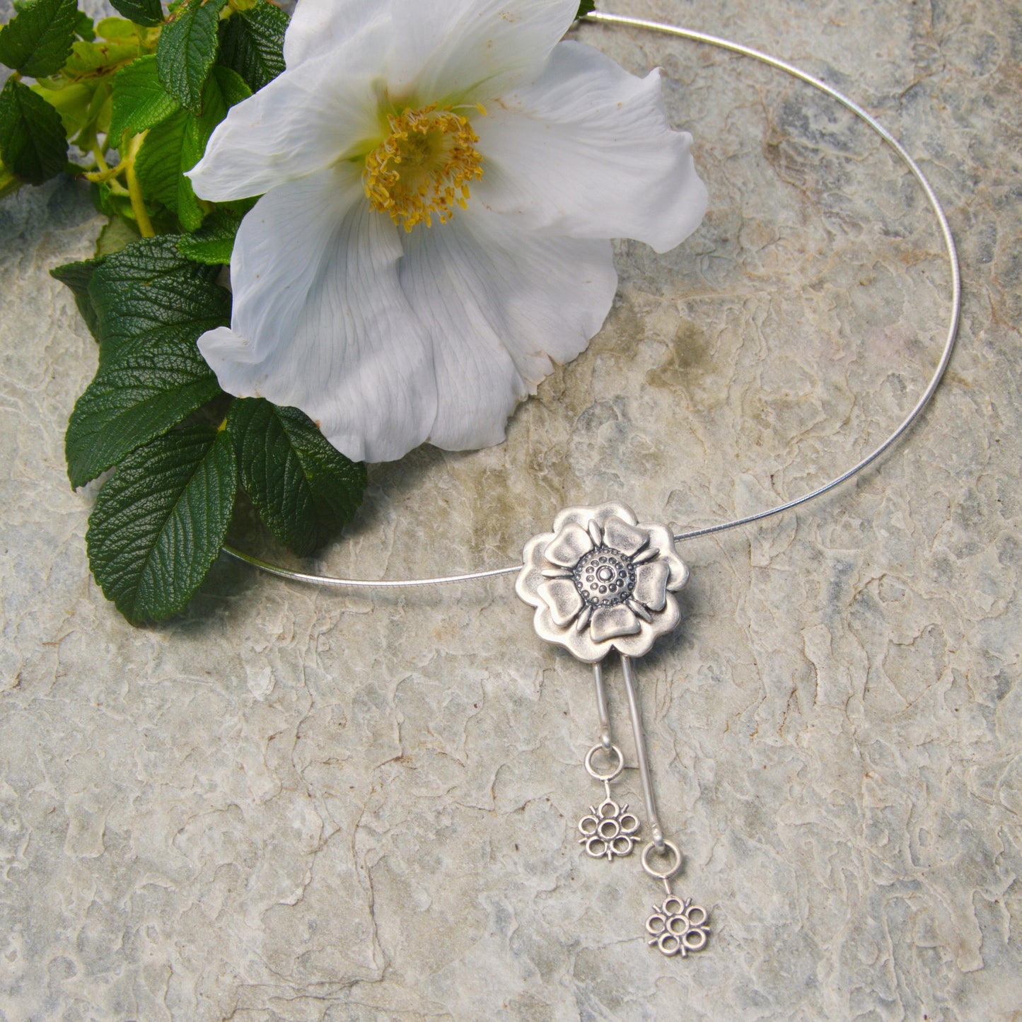Outlander Jacobite Rose Coin Collection necklace with rose charm and drop detail on a slate background with rose by Aurora Jewellery, Orkney, Scotland