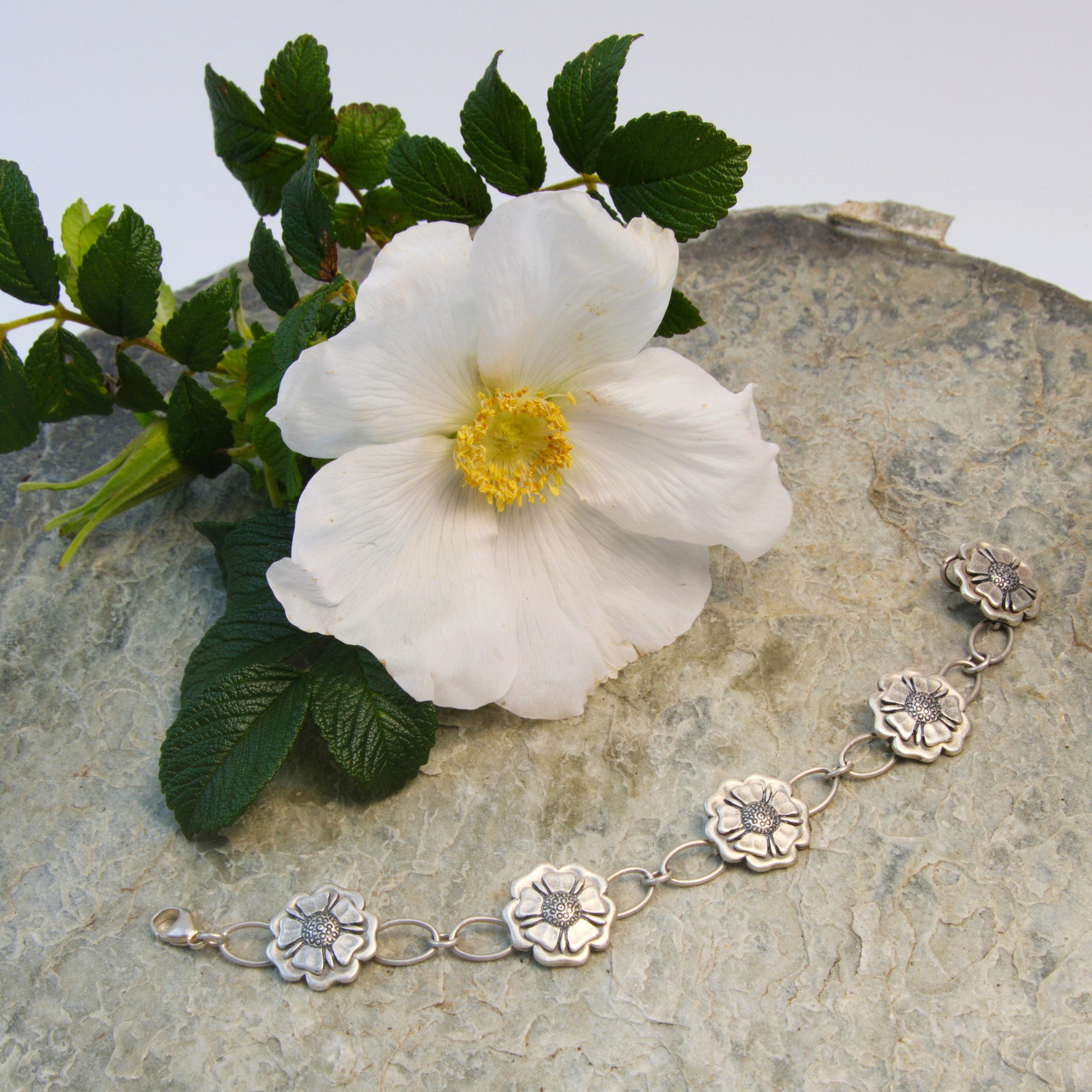Outlander Rose Coin Collection Bracelet on a slate background with rose by Aurora Jewellery, Orkney, Scotland