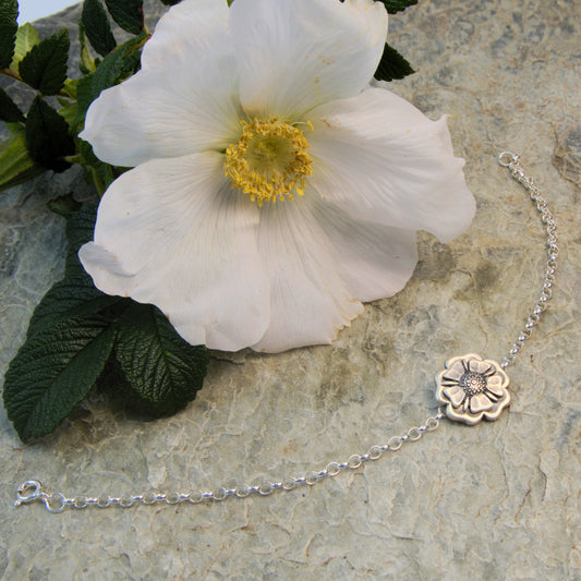 Outlander Jacobite Rose Coin Collection single charm bracelet with rose charm on a slate background with rose by Aurora Jewellery, Orkney, Scotland