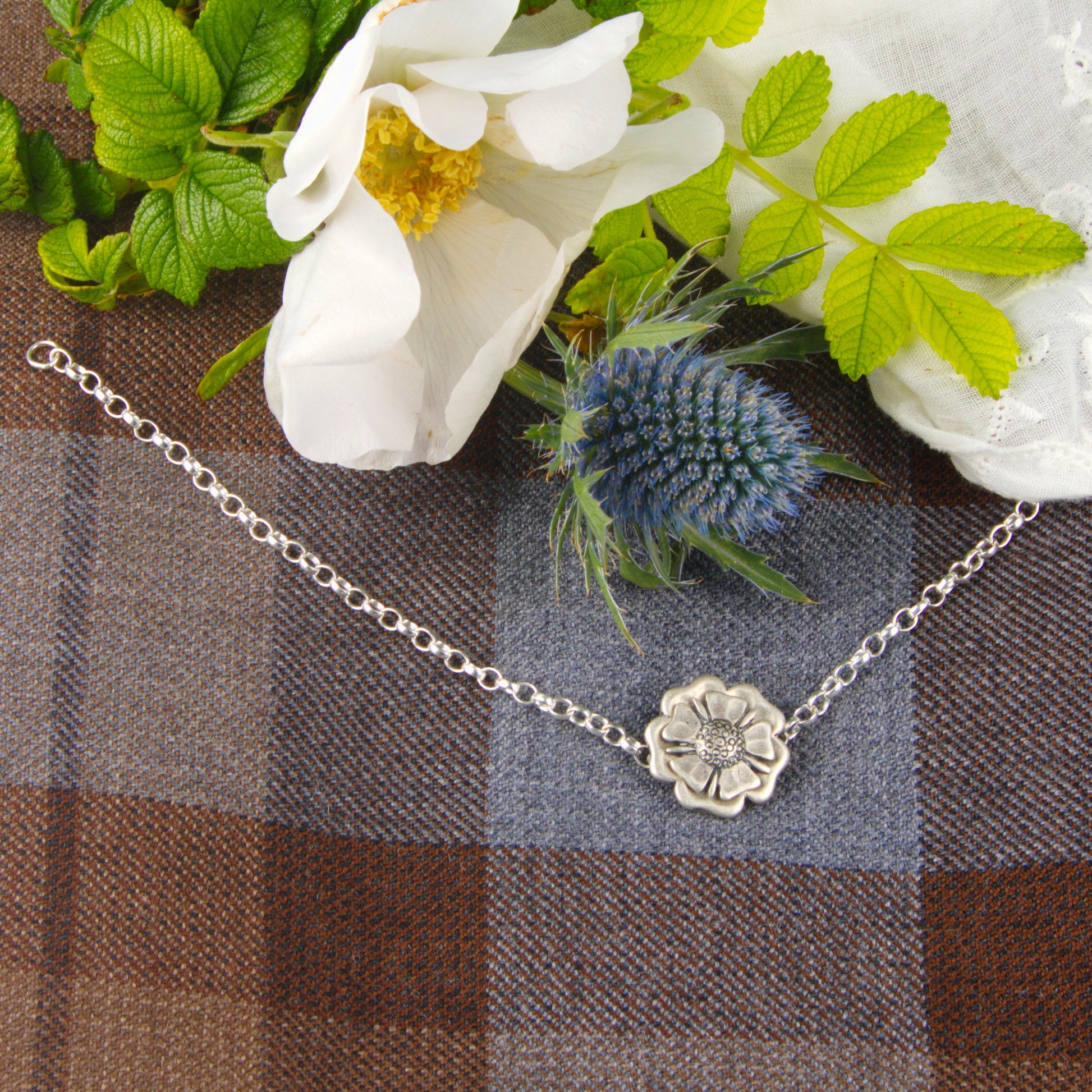 Outlander Jacobite Rose Coin Collection single charm bracelet with rose charm on a tartan background with rose by Aurora Jewellery, Orkney, Scotland