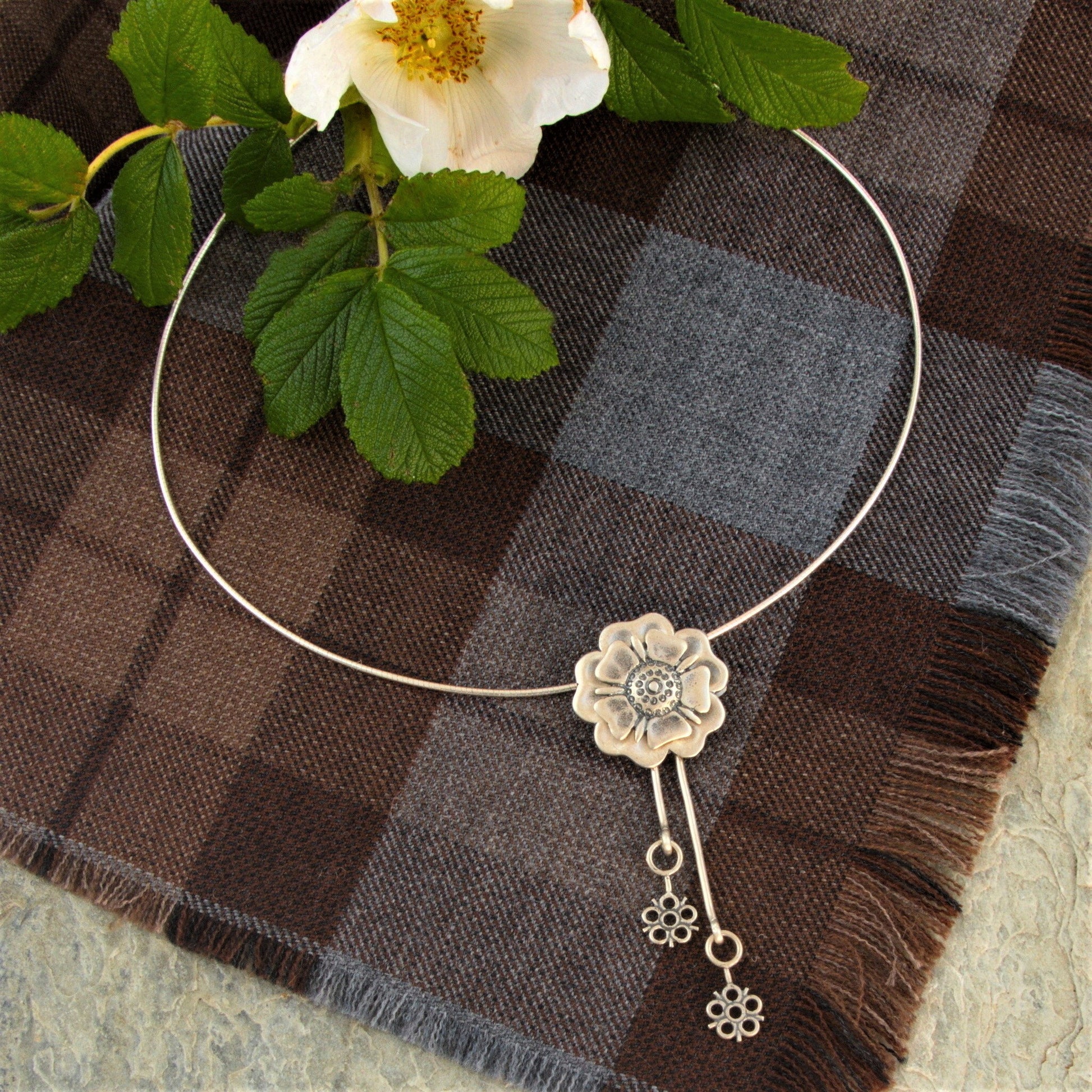 Outlander Jacobite Rose Coin Collection necklace with rose charm and drop detail on a tartan background with rose by Aurora Jewellery, Orkney, Scotland